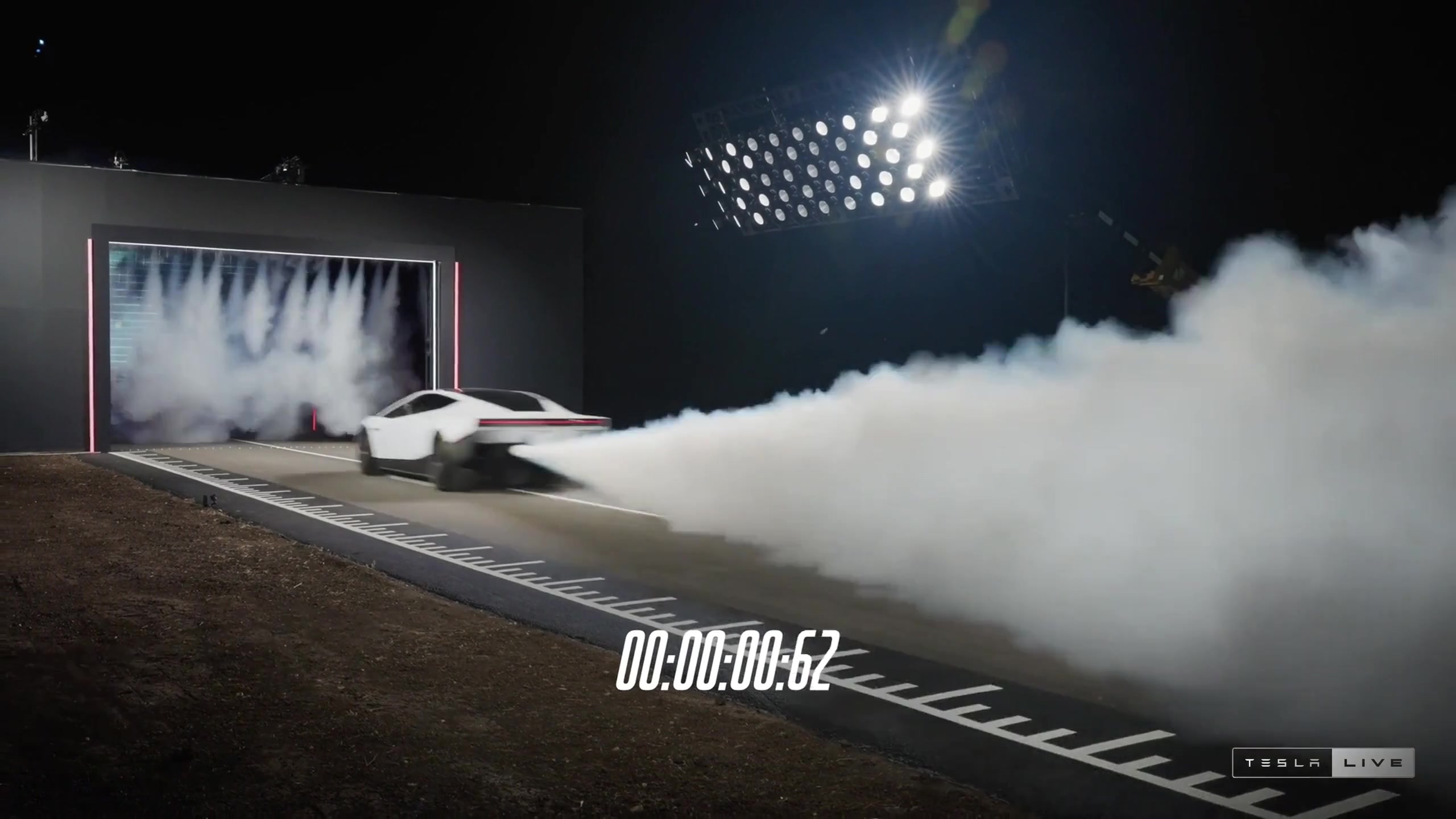 Tesla Roadster launching on a drag strip with thruster gas behind it and a timer on screen