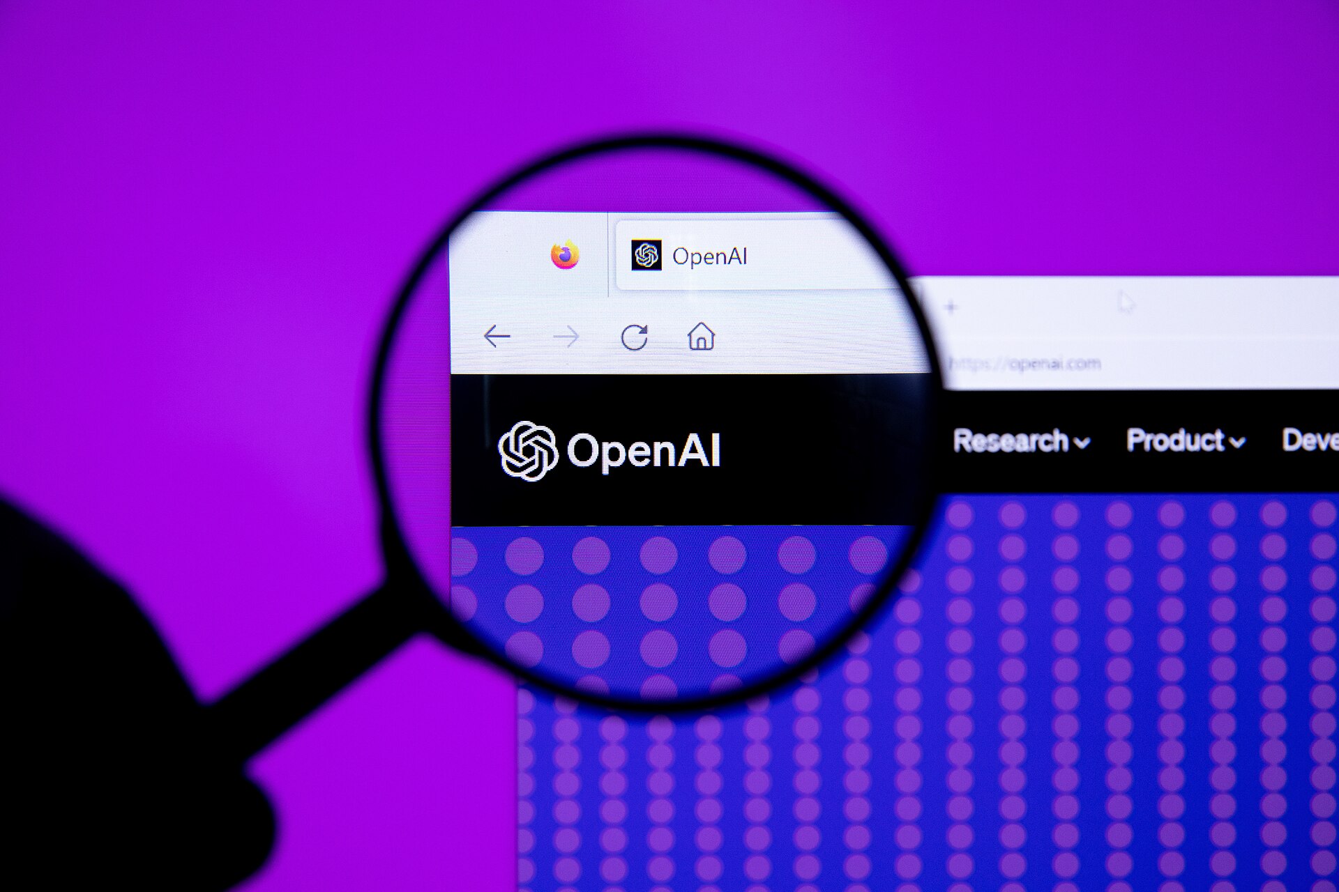 OpenAI logo on its website seen through a magnifying glass