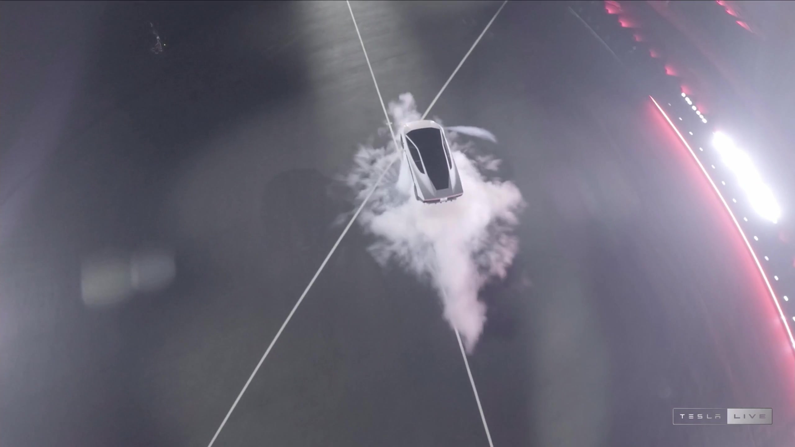 Aerial view of the Tesla Roadster rolling in midair in a cloud of cold gas after leaving the ramp